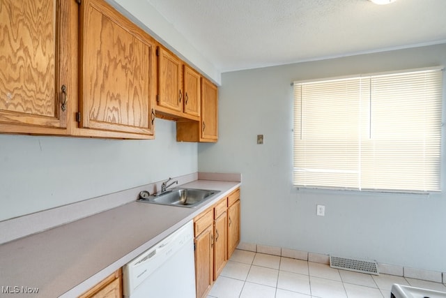 kitchen featuring visible vents, white dishwasher, light countertops, a sink, and light tile patterned floors