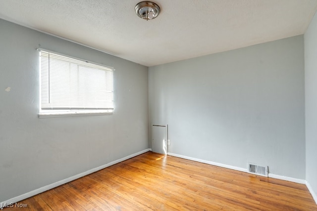 empty room with baseboards, visible vents, and wood finished floors