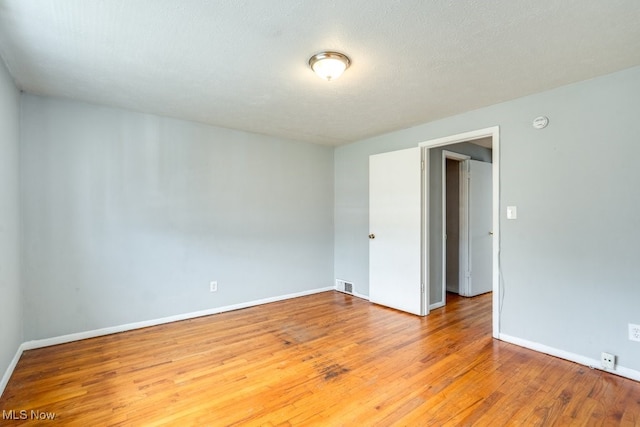unfurnished room featuring visible vents, baseboards, and wood finished floors