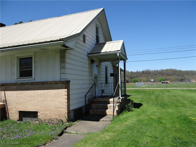 view of side of home with board and batten siding, a yard, metal roof, and brick siding