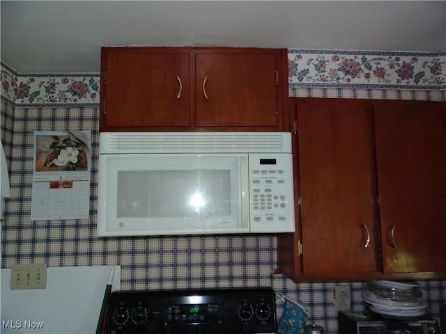 details with stove, white microwave, and wallpapered walls