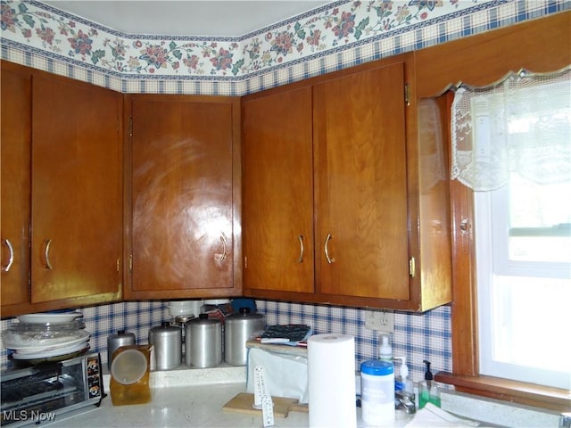 interior space with a toaster, brown cabinetry, and wallpapered walls