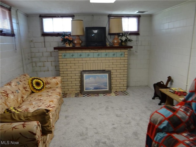 living area featuring concrete block wall, plenty of natural light, carpet, and a fireplace