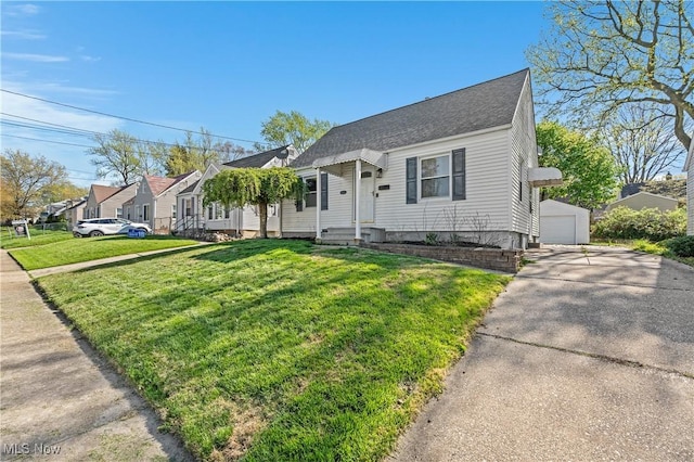 view of front of house with a garage, a front yard, a shingled roof, an outbuilding, and a residential view