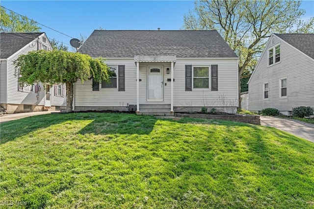 cape cod home featuring entry steps, roof with shingles, and a front lawn