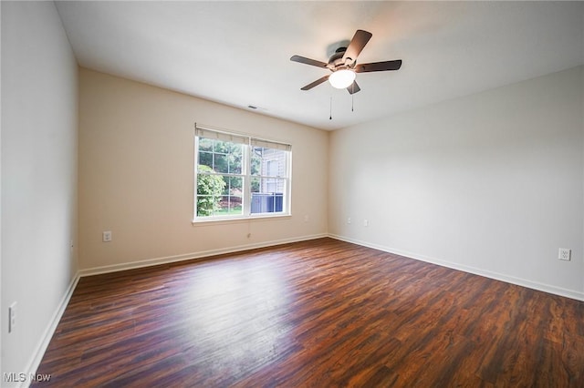 spare room featuring ceiling fan, dark wood finished floors, baseboards, and visible vents