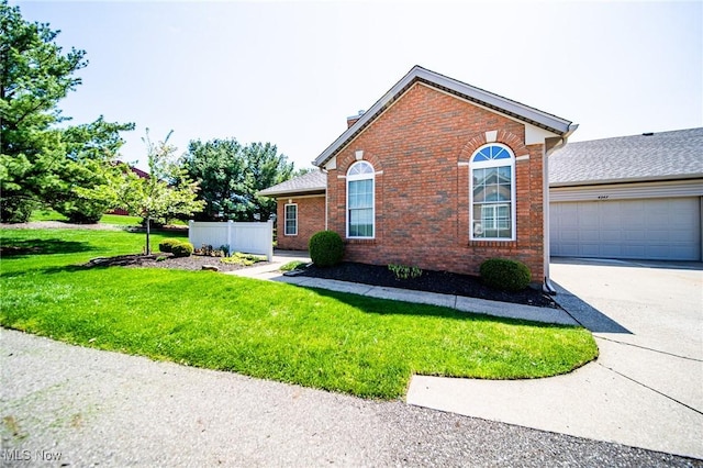 view of front facade featuring an attached garage, a front lawn, brick siding, a chimney, and driveway