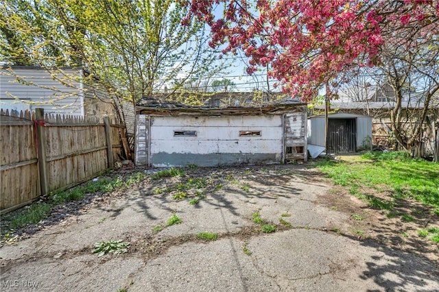 detached garage with fence and a storage shed