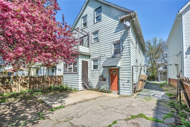 view of front of house featuring fence, a patio, and a balcony