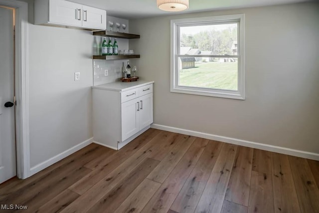bar featuring baseboards, a dry bar, and wood finished floors