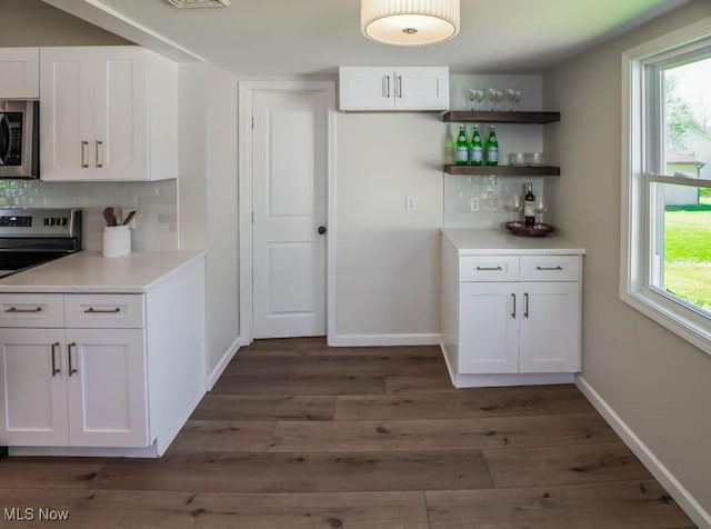 kitchen featuring decorative backsplash, baseboards, stainless steel appliances, white cabinetry, and dark wood-type flooring