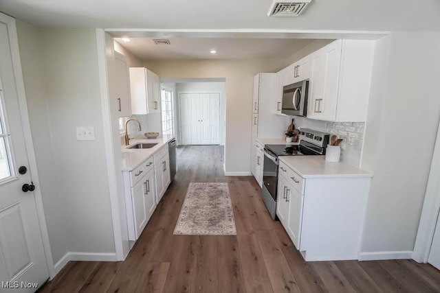kitchen with a sink, appliances with stainless steel finishes, backsplash, and light countertops