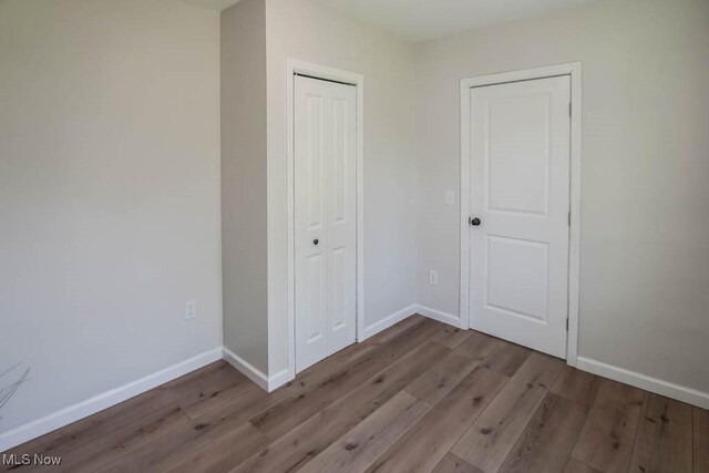 unfurnished bedroom featuring baseboards, a closet, and wood finished floors