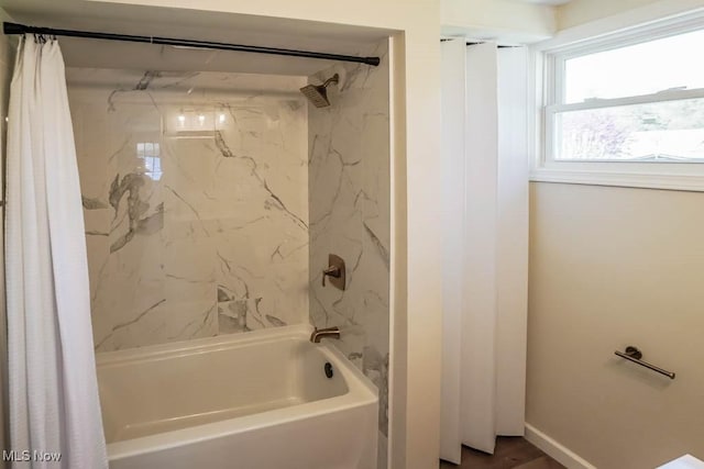 bathroom featuring baseboards and shower / bath combo