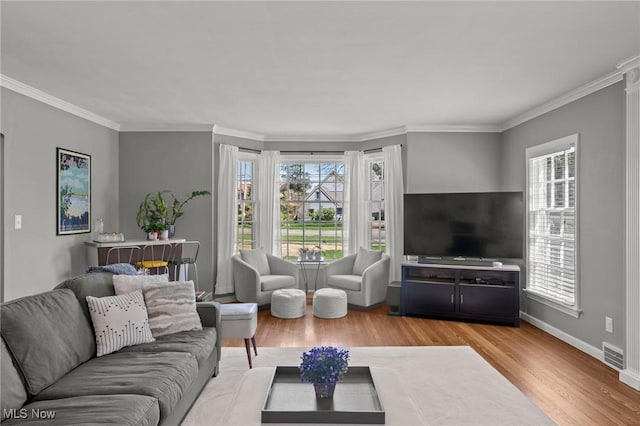 living area with crown molding, baseboards, visible vents, and light wood-style floors