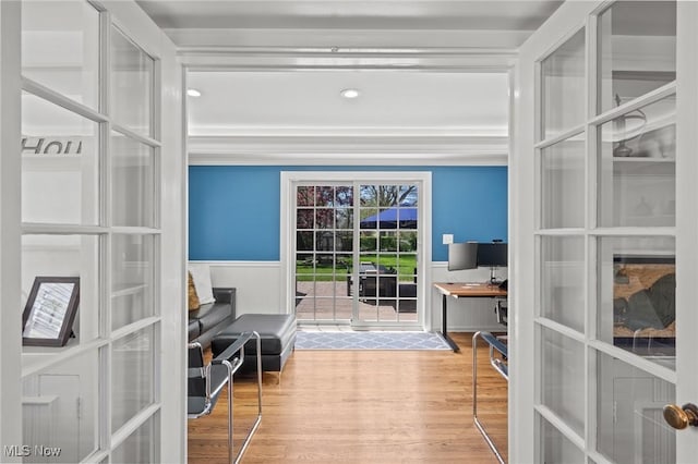 doorway to outside with ornamental molding, wainscoting, french doors, and wood finished floors