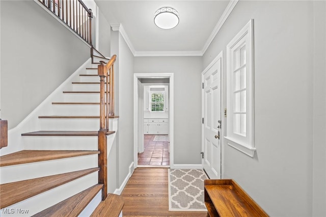 foyer with ornamental molding, stairs, and wood finished floors