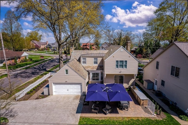 exterior space with concrete driveway, a residential view, a patio area, and a garage