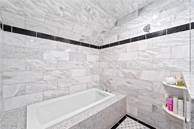 full bath with tiled bath and tile walls