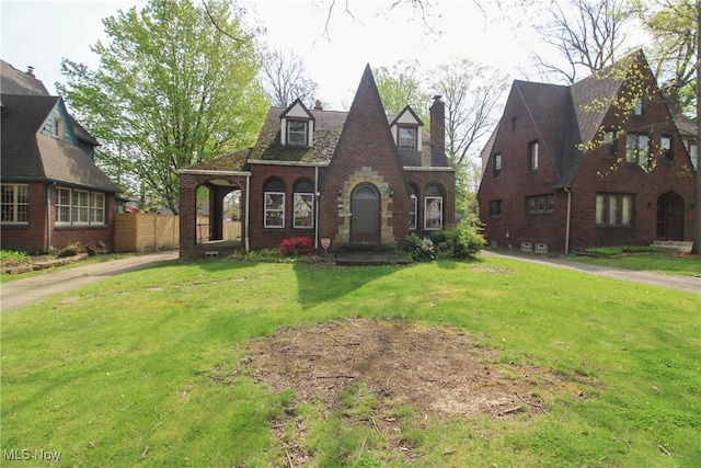 132 Jennette Dr, Boardman, OH 44512 - tudor-style house with brick siding, fence, a chimney, and a front yard