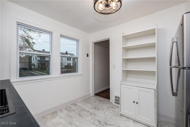 unfurnished dining area with visible vents, marble finish floor, baseboards, and built in features