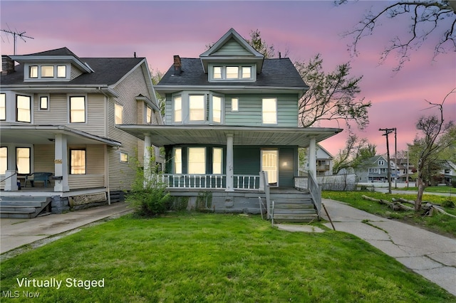 american foursquare style home with a yard and covered porch