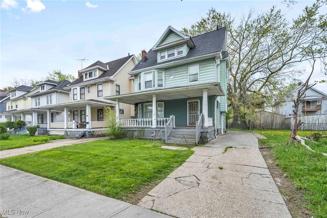 view of front of house with a porch, fence, and a front yard