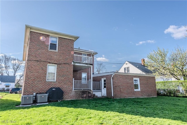 rear view of property with a lawn, brick siding, and central air condition unit