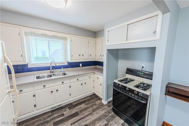 kitchen featuring white cabinets, a sink, light countertops, dark wood finished floors, and gas range