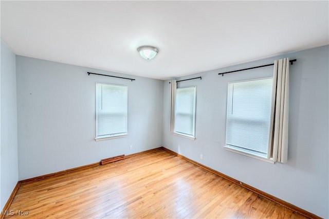 spare room with a healthy amount of sunlight, baseboards, and light wood finished floors
