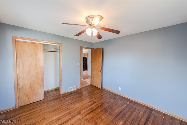 unfurnished bedroom with visible vents, a closet, wood finished floors, baseboards, and ceiling fan