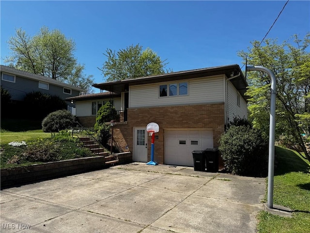 view of front of property featuring brick siding, a garage, stairs, and driveway