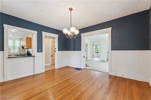 162 S Cedar St, Oberlin, OH 44074 - empty room featuring light wood finished floors, a chandelier, wainscoting, and a textured ceiling