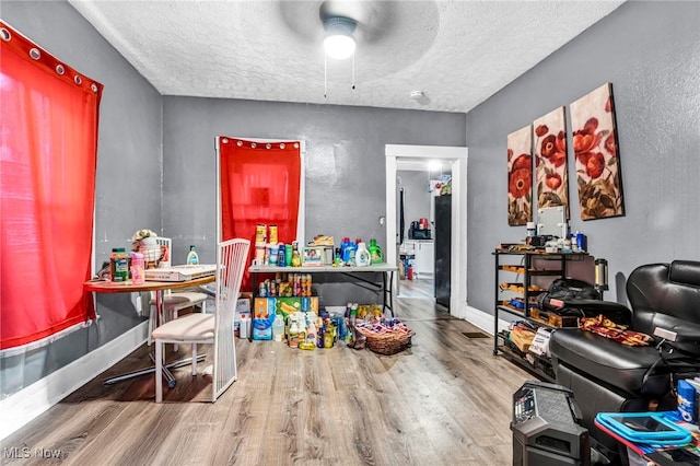 recreation room with a ceiling fan, a textured ceiling, and wood finished floors