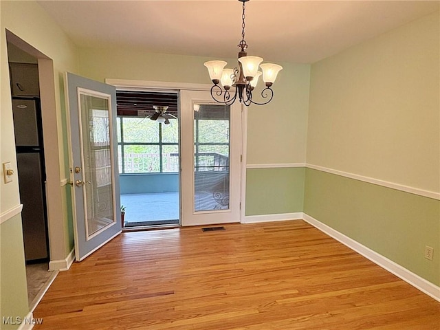 unfurnished dining area with light wood-style floors, baseboards, visible vents, and an inviting chandelier