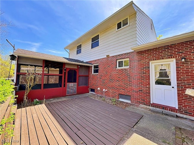 rear view of property with a sunroom, a wooden deck, and brick siding
