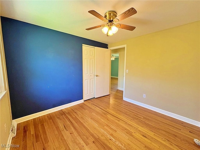 empty room with baseboards, ceiling fan, and wood finished floors