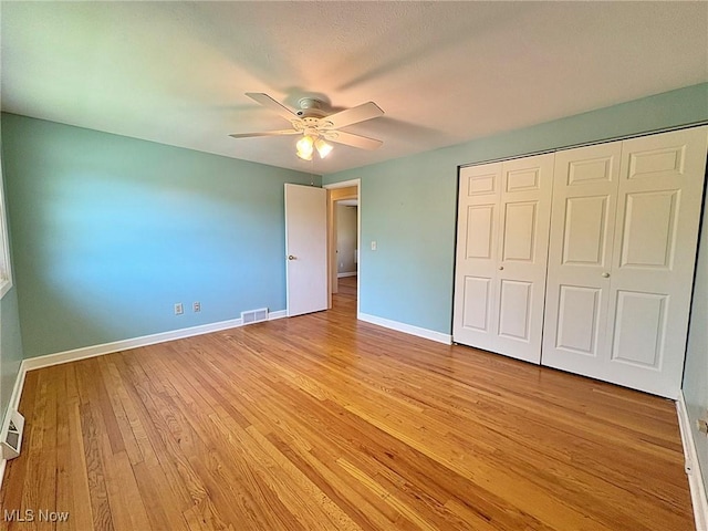 unfurnished bedroom with visible vents, a closet, baseboards, ceiling fan, and light wood finished floors
