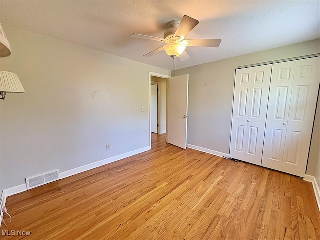 unfurnished bedroom featuring baseboards, visible vents, light wood-style flooring, and a closet