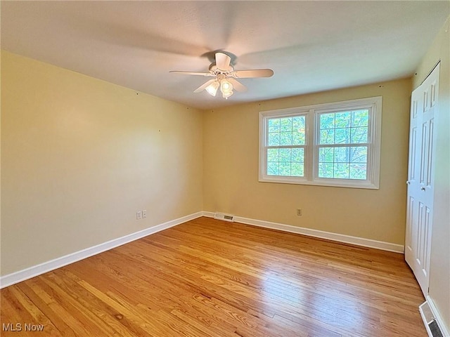 empty room featuring baseboards, light wood finished floors, ceiling fan, and visible vents