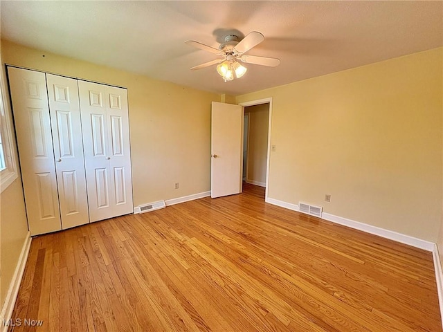 unfurnished bedroom with visible vents, light wood-style flooring, baseboards, and a closet
