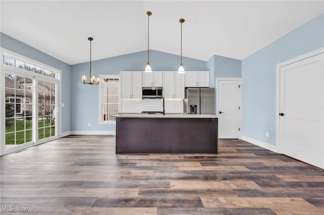 kitchen with appliances with stainless steel finishes, tasteful backsplash, vaulted ceiling, an inviting chandelier, and white cabinetry