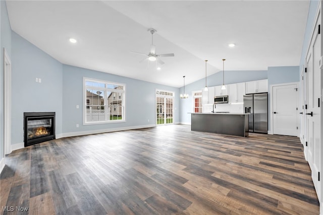 unfurnished living room with a ceiling fan, dark wood-style flooring, a sink, lofted ceiling, and a glass covered fireplace