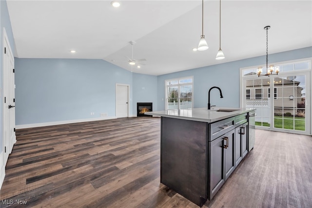 kitchen featuring a sink, a glass covered fireplace, dark wood-style floors, and ceiling fan with notable chandelier