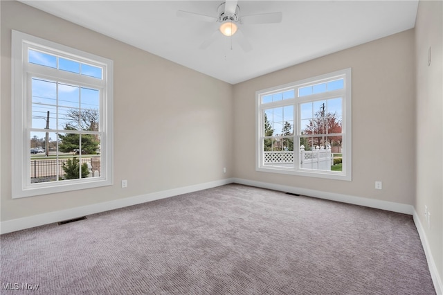 carpeted empty room featuring a ceiling fan, baseboards, visible vents, and a wealth of natural light