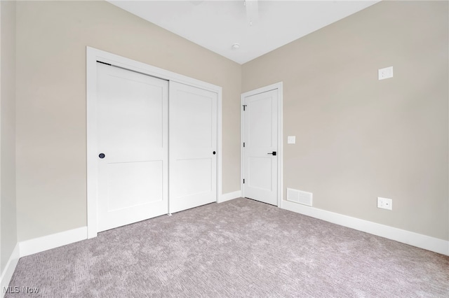 unfurnished bedroom featuring carpet floors, baseboards, a closet, and visible vents