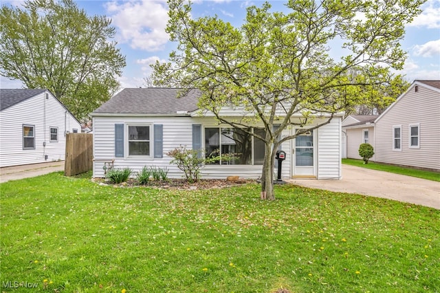 view of front of property featuring a shingled roof, a front lawn, and fence