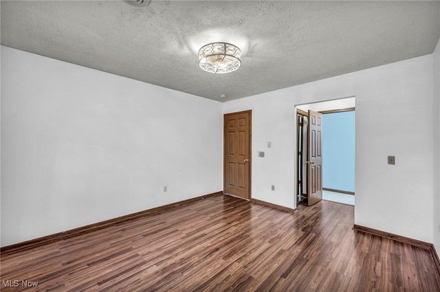 empty room with baseboards, a textured ceiling, and wood finished floors