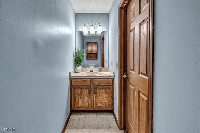 bathroom with baseboards, vanity, a textured ceiling, and a chandelier