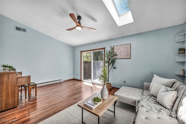living room featuring ceiling fan, a textured ceiling, visible vents, baseboard heating, and wood finished floors